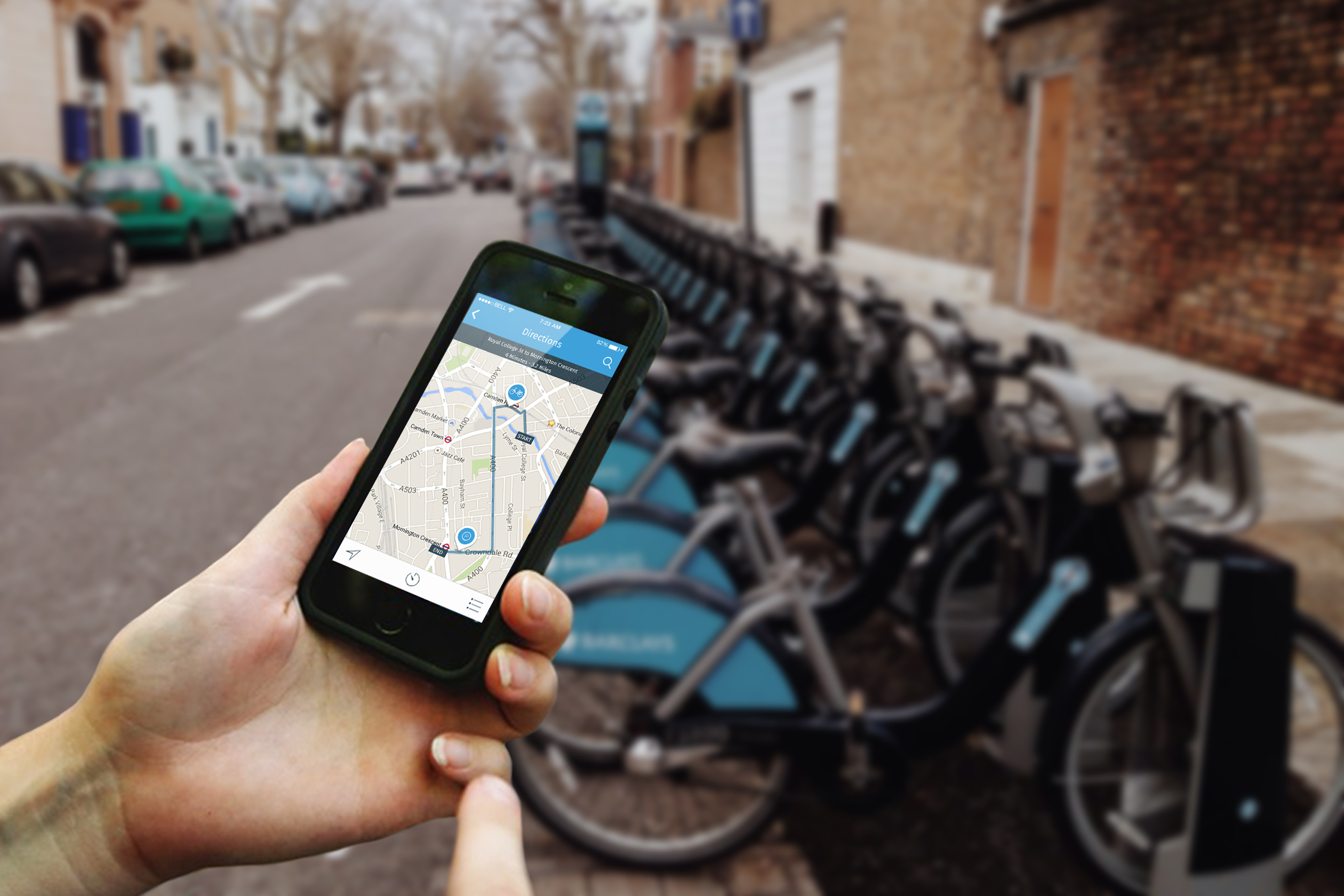 Hands holding an iPhone showing the London by Bike App Nearby Map screen.