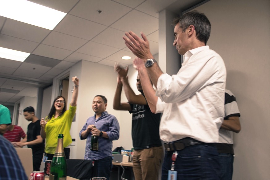 A photo of 5 senior members of the Amazon Music team clapping and poping champagne.